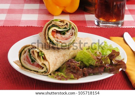 Smoked turkey pesto wraps on a bed of red lettuce