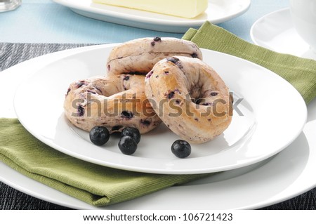 A plate of mini bagels with fresh blueberries and butter