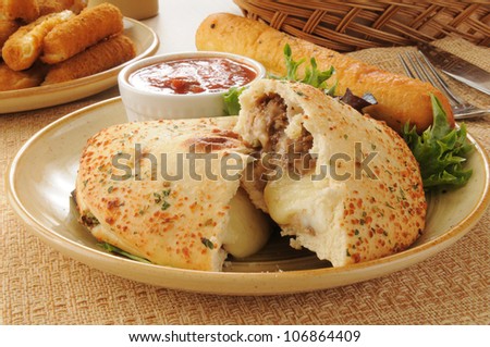 Close up of a steak and cheese calzone with mozzarella and bread sticks