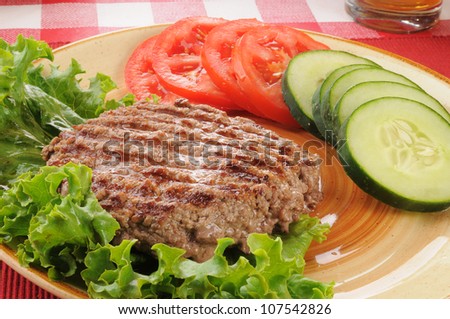 A juicy grilled ground beef patty with cucumbers nad lettuce