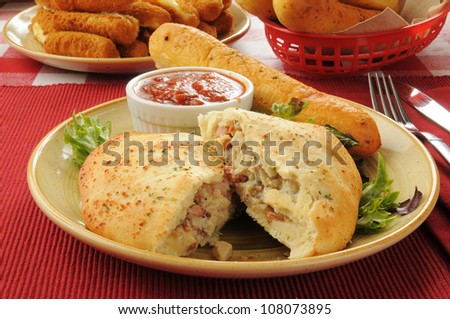Steak and cheese calzone with bread and mozzarella cheese sticks