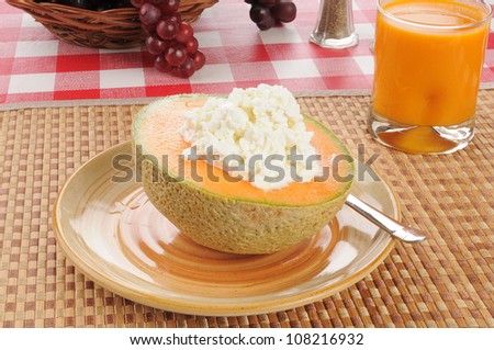 A cantaloupe with cottage cheese and mango juice