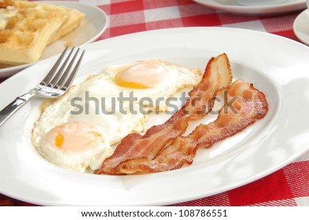 Close up of bacon and eggs with a waffle