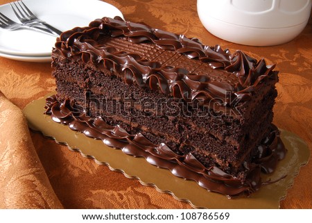 A gourmet chocolate cake with a coffee pot and serving plates