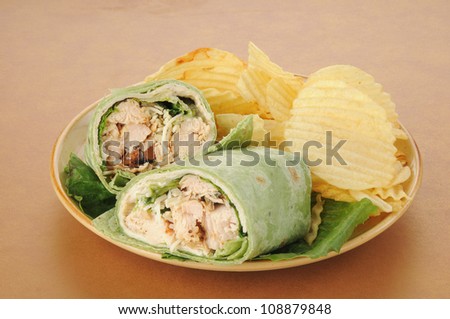 A plate of chicken caesar wraps with potato chips