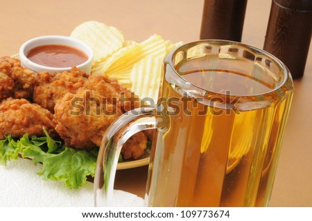 Closeup of a mug of beer with chicken wings and potato chips