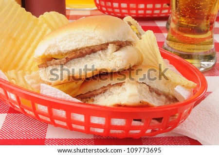 A basket of sliders, or mini cheeseburgers, and potato chips with beer