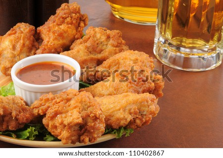 A plate of chicken wings with barbecue sauce and beer