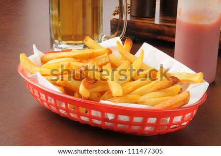 A basket of french fries and a mug of beer on a bar counter