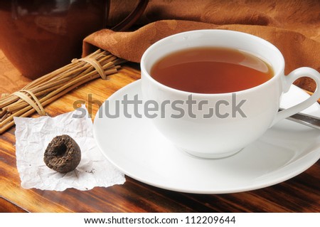 A cup of tea with a button of Puerh Tea, a delicious fermented tea from China