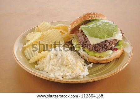 A guacamole burger with chips and coleslaw