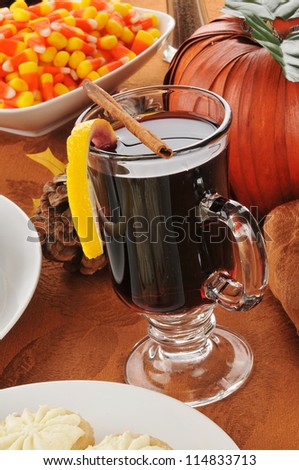 A mug of hot spice wine with a lemon twist and candy corn on a Halloween or Thanksgiving table