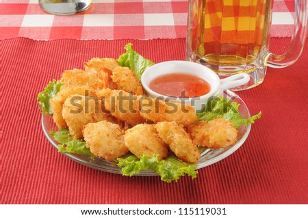 A plate of shrimp with sweet chili sauce and a mug of beer