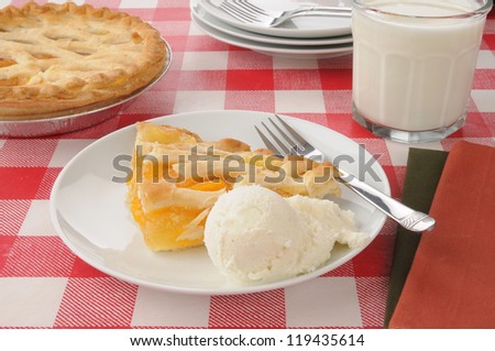 A slice of peach pie with vanilla ice cream and milk