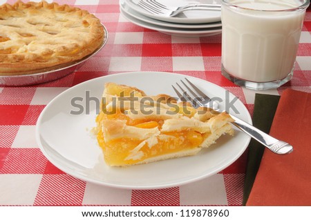 A slice of peach pie with a glass of milk