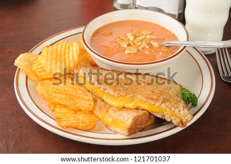 Cheese sandwich with tomato soup and chips served in a classic American diner setting