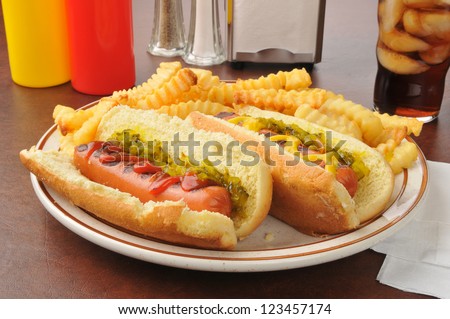 A plate of hot dogs with relish and french fries