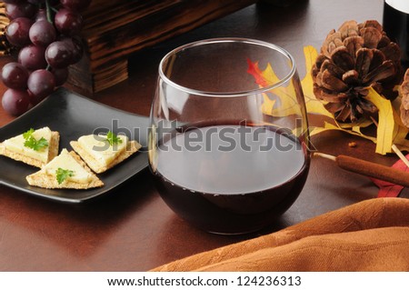 A glass of red wine with cheese and crackers