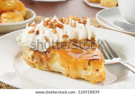 A slice of cream pie with caramel, whipped cream and nuts