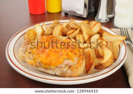 An open faced tuna melt with potato wedges and a glass of milk