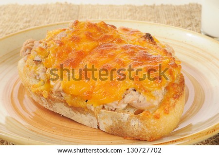 Close up of a tuna melt with a glass of milk