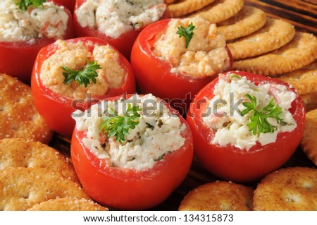 A party setting with tomatoes stuffed with crab and spinach dip and crackers