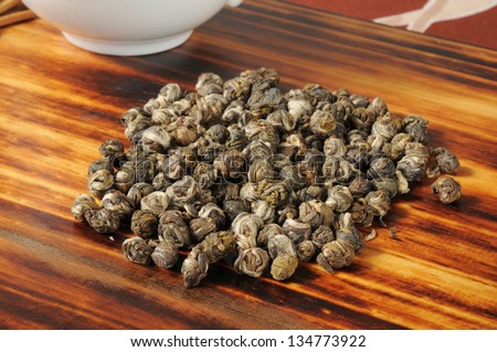 A mound of Jasmine green tea pearls near a cup of tea