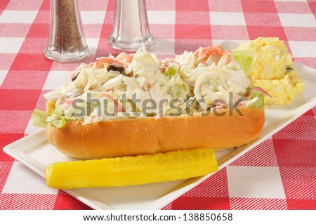 A seafood sandwich on a deli roll with potato salad