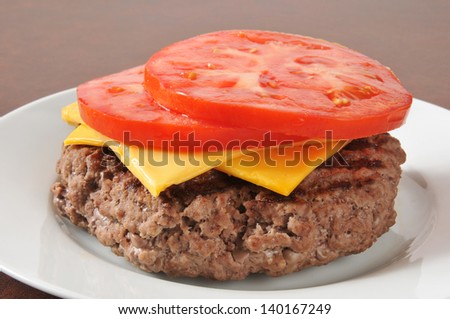 A hamburger patty with tomato and cheese slices