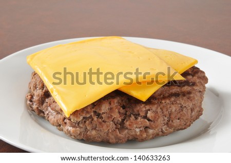 A thick hamburger patty with slices of American or Cheddar cheese