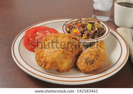 Fried chicken dinner with quinoa salad and sliced tomatoes