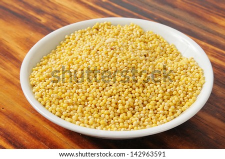 A small bowl of hulled millet on a cutting board