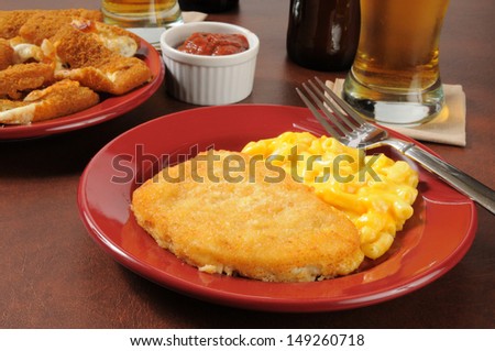 Fish sticks with macaroni and cheese, mozzarella cheese sticks and beer on a bar counter with beer