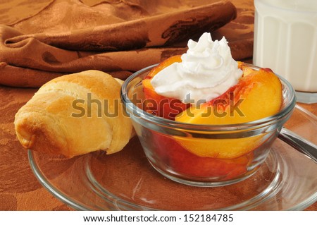 A fresh baked croissant and peaches with whipped cream