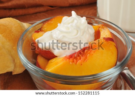 Closeup of a bowl of sliced peaches with whipped cream and a croissant