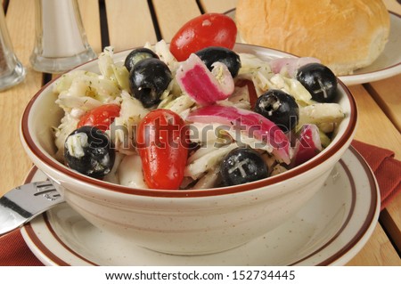 A bowl of greek style cole slaw with olives, tomatoes, feta cheese and red onions