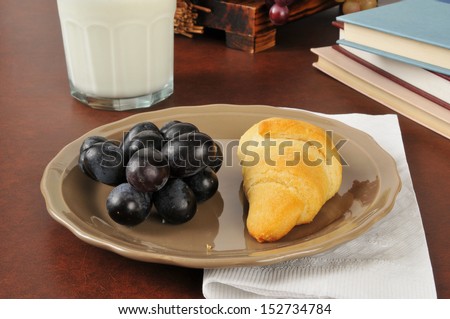 A croissant, grapes and milk as an after school snack