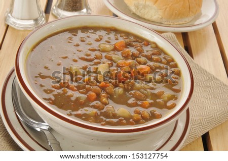 A bowl of healthy lentil soup with a dinner roll
