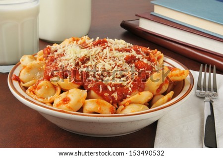 A bowl of leftover tortellini with marina sauce and parmesan cheese as an after school snack or meal