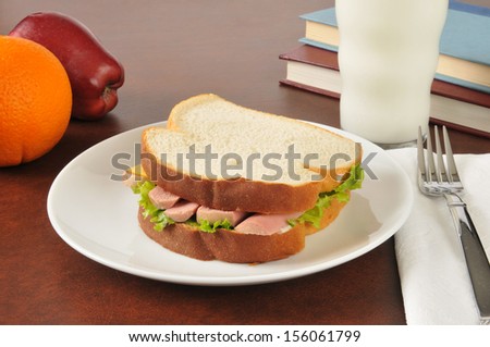 A vienna sausage sandwich with an apple, orange and a glass of milk as an after school snack