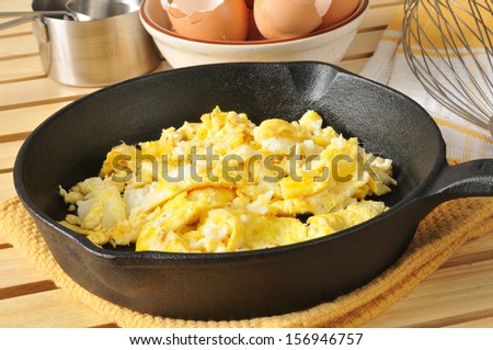 Fresh cooked scrambled eggs in a cast iron skillet with brown egg shells in the background