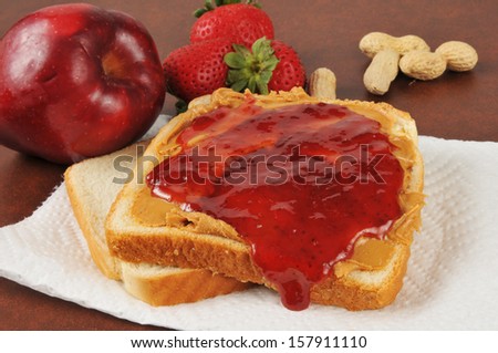 Bread with peanut butter and strawberry jam, with an apple