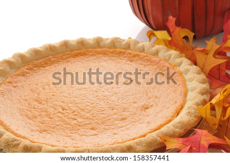 A whole pumpkin pie with autumn leaves and a decorative pumpkin