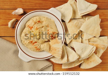 Garlic spice hummus from above on a rustic wood table with pita bread wedges