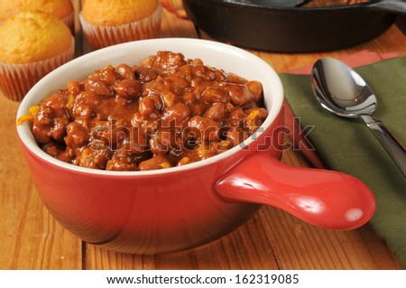 A bowl of chili con carne with cornbread muffins