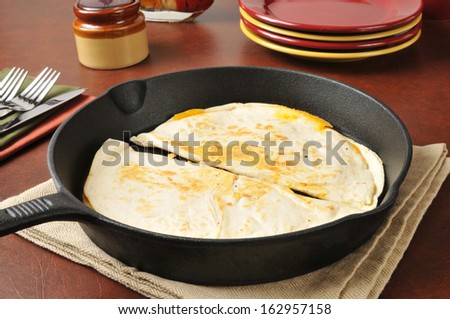 Quesadillas in a cast iron skillet with serving plates