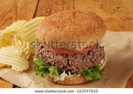 A thick hamburger on butcher paper with potato chips