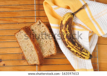 Banana bread and a fresh banana on a cooling rack