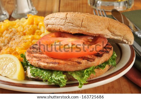 Closeup of a salmon burger on a whole wheat bun with macaroni and cheese