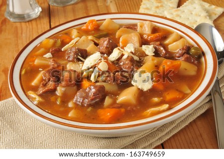 A bowl of vegetable beef soup on a rustic wooden table
